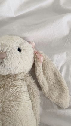 a white stuffed animal laying on top of a bed