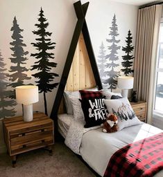 a bedroom decorated in black and white with trees on the wall