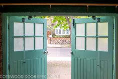 an open green door leading to a brick building with trees in the backgroud