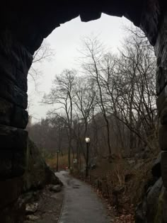 an arch in the side of a stone wall with a street light on it's side