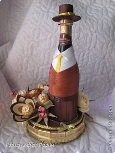 a wine bottle is sitting on top of a gold plated stand with flowers in it