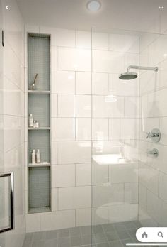 a white tiled bathroom with shelves on the wall