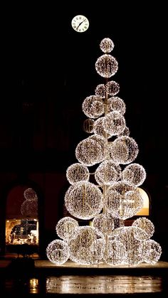 a lighted christmas tree in front of a clock