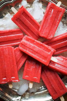 red popsicles are sitting on top of ice in a metal bowl with toothpicks sticking out of them