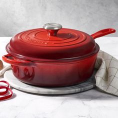 a red cast iron casserole sitting on top of a white counter