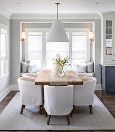 the dining room table is surrounded by white chairs and an upholstered area for seating