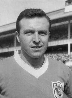 a black and white photo of a man wearing a soccer uniform in front of a stadium