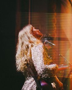 a woman standing in front of a microphone on stage