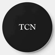 a black and white clock with the word tcn on it's face in cursive font