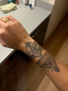 a woman's arm with a tattoo on it and a gold ring in the middle