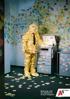 a man in a yellow suit and tie standing next to a filing cabinet with papers all over it