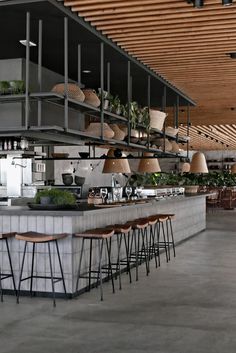 an industrial style bar with stools and plants on the shelves above it in a restaurant