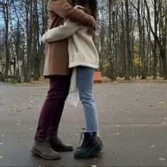 two people standing next to each other with an umbrella over their heads and trees in the background