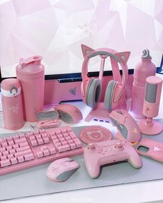 a computer desk topped with pink items like headphones, keyboard and mouse on top of it