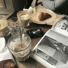 a table topped with plates and glasses filled with liquid next to an open book on top of a wooden table