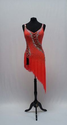 an orange flap dress with sequins and fringe on the skirt is sitting on a mannequin