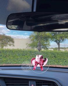 a car dashboard with a pink bow hanging from the front window and an antenna attached to it