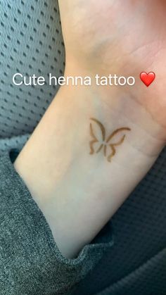 a small tattoo on the wrist of a person with a red heart in the background