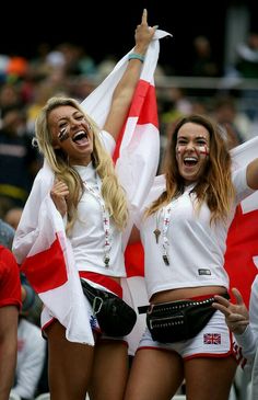 two beautiful women in white outfits holding flags