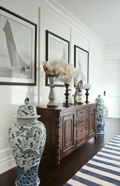 two blue and white vases sitting on top of a wooden table next to pictures