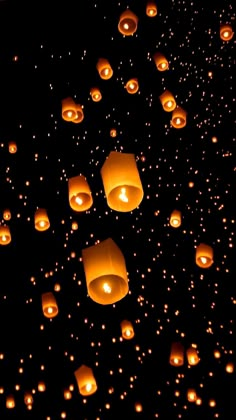 many lit up lanterns floating in the air