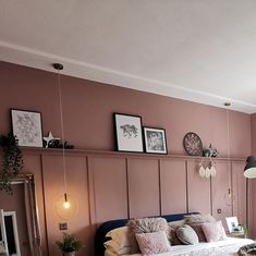 a bedroom with pink walls and white bedding in the corner, along with pictures on the wall