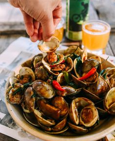 a plate full of mussels with beer in the background