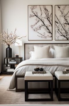 a bedroom with two paintings above the bed and foot stools in front of it