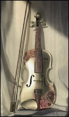 an old violin is sitting on a white sheet and has pink flowers painted on it