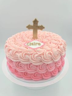 a cake with pink frosting and a gold cross on top