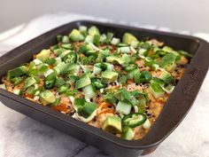 a casserole dish with vegetables and cheese in it on a white tablecloth