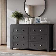 a black dresser with drawers and a round mirror