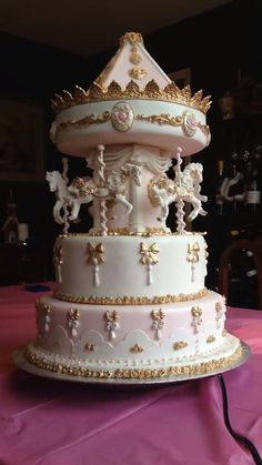 a three tiered white cake with gold trimmings and decorations on the top