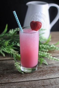 a strawberry drink in a glass with a straw on the top and green leaves around it