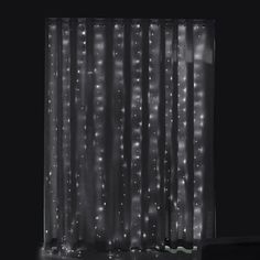 a black and white photo of curtains with lights on the outside, in front of a window