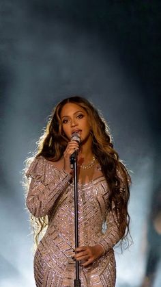 a woman in a gold dress holding a microphone