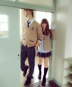 a young man and woman standing in front of a door with their arms around each other