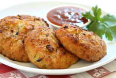 three crab cakes on a white plate with sauce and cilantro garnish