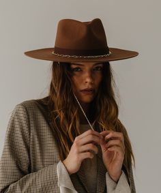 Think of the Raine as three hats in one. The removable paperclip brass chain features three pearls, + our first ever chain chinstrap can stay clipped into the hat or not, it’s totally up to you. Strip the Raine down to its basic form, the wide brim fedora, to showcase a hand-sewn grosgrain band with the gold Gigi Pip bar. This is a hat for a woman who loves options. Black Brimmed Western Fedora, Luxury Black Western Felt Hat, Western-themed Wide Brim Rigid Fedora, Black Western Brimmed Hat, Western Wide-brim Fedora With Feathers, Wide Brim Fedora, Halo Style, Find Color, Wearing A Hat