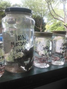 mason jars with writing on them sitting on a window sill in front of a tree