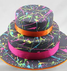 three tiered hats with colorful splatters and ribbons on the top one has an orange ribbon