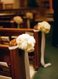 two white flowers are sitting on the pews