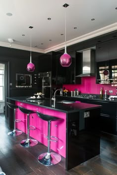 a kitchen with black cabinets and pink counter tops, two bar stools in front of the island