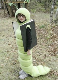 a young boy dressed as a caterpillar holding a book in his hands and wearing glasses