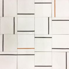 a white tiled wall with black and orange lines on it's sides, as well as squares