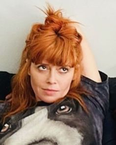 a woman with red hair is posing for a photo while holding her head up to the side