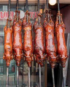 several skewers of meat hanging in front of a store window with the word hot dog on it