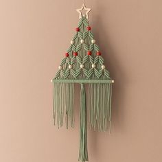 a green christmas tree hanging from the side of a wall with beads and tassels