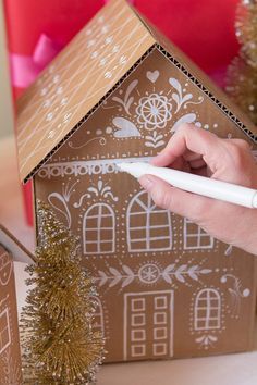 a hand writing on a piece of paper next to a gingerbread house with decorations