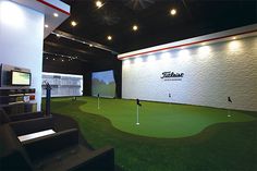 an indoor golf course with green grass and white brick walls, lights on the ceiling